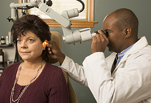 Un médico examina el oído de una paciente.