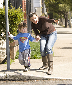 Mujer que toma de la mano a un niño pequeño para cruzar la calle.