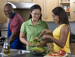 Familia preparando una ensalada en la cocina.